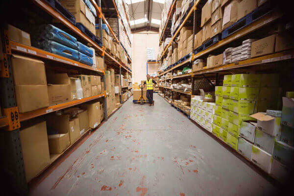 Worker with trolley of boxes in a large warehouse