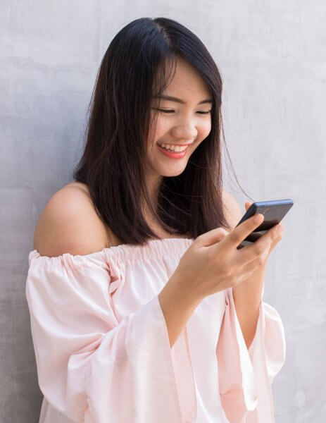 beautiful asian woman using cellphone, over concrete wall